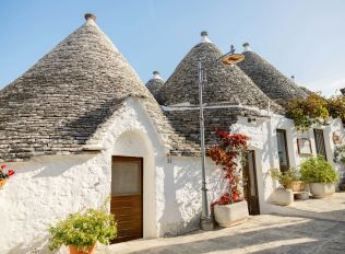a house with blue doors and a roof with a blue door with Alberobello in the background