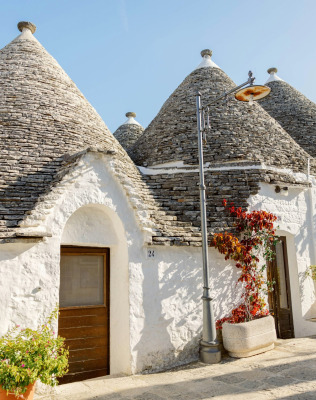 a house with blue doors and a roof with a blue door with Alberobello in the background