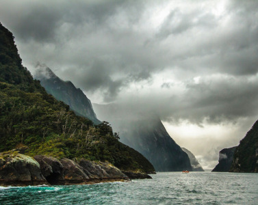 peak of mountain covered with clouds near body of water