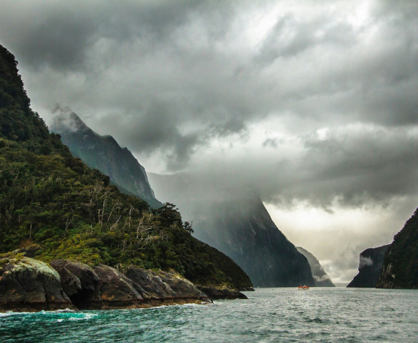 peak of mountain covered with clouds near body of water