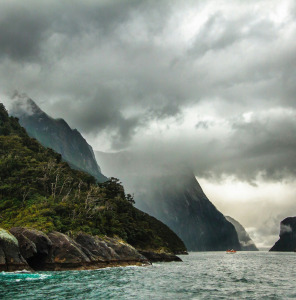peak of mountain covered with clouds near body of water