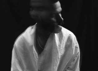 Black and white of lonely melancholic male in white shirt shaking head in motion sitting against black background