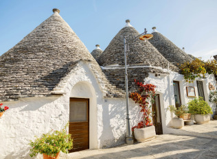 a house with blue doors and a roof with a blue door with Alberobello in the background