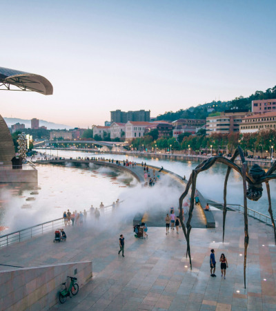 a large spider sculpture in front of a body of water