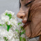 A woman is smelling a bunch of flowers.