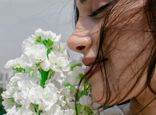 A woman is smelling a bunch of flowers.