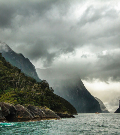 peak of mountain covered with clouds near body of water