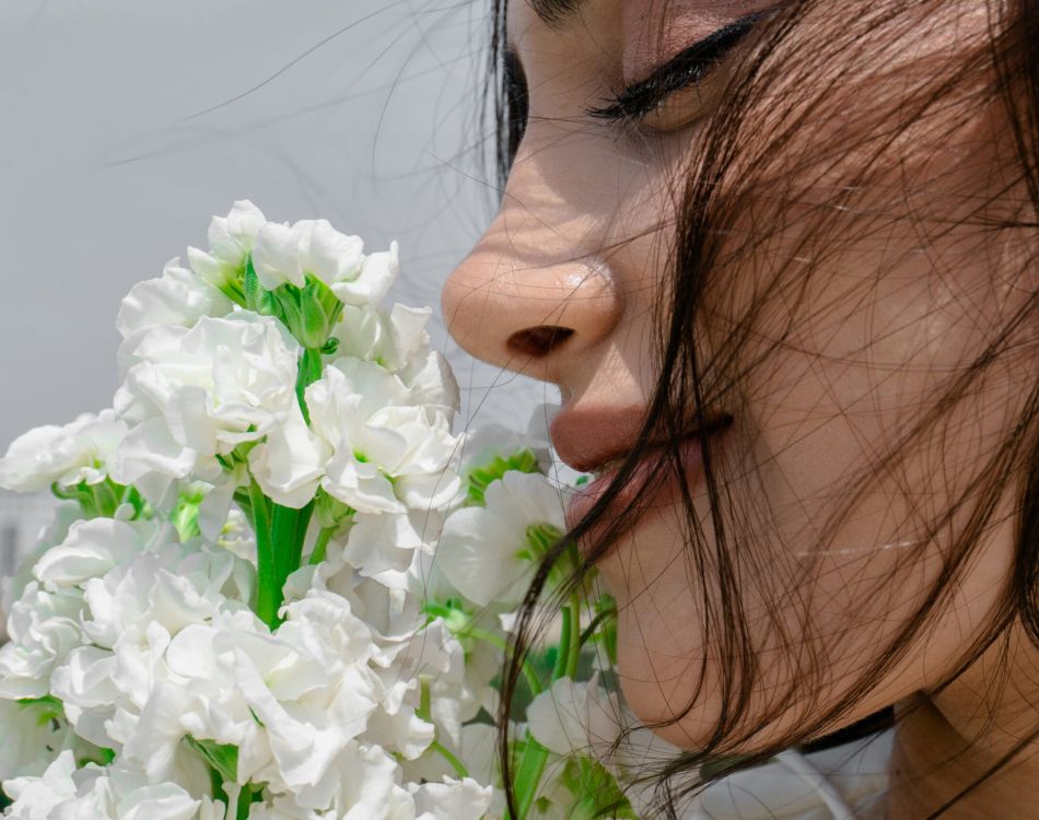 A woman is smelling a bunch of flowers.
