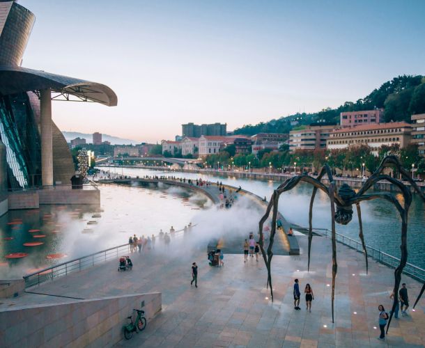 a large spider sculpture in front of a body of water