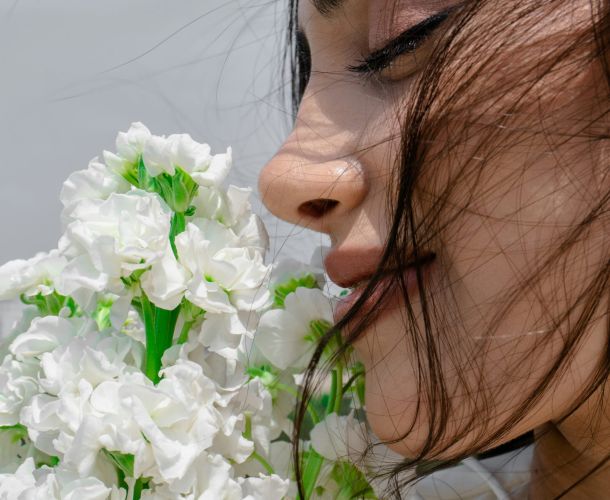 A woman is smelling a bunch of flowers.