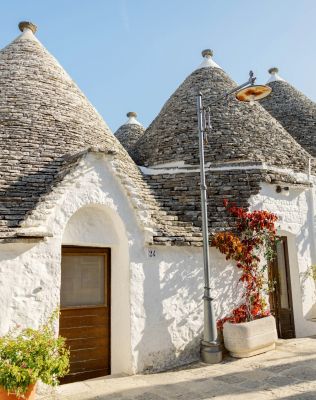 a house with blue doors and a roof with a blue door with Alberobello in the background