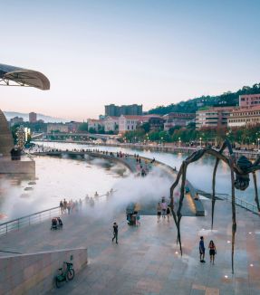 a large spider sculpture in front of a body of water