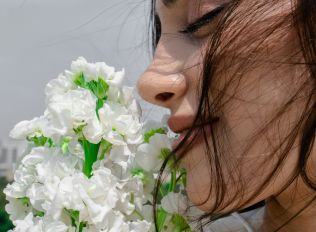 A woman is smelling a bunch of flowers.
