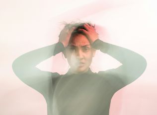 man sitting on gang chair with feet on luggage looking at airplane
