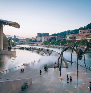 a large spider sculpture in front of a body of water