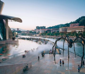 a large spider sculpture in front of a body of water