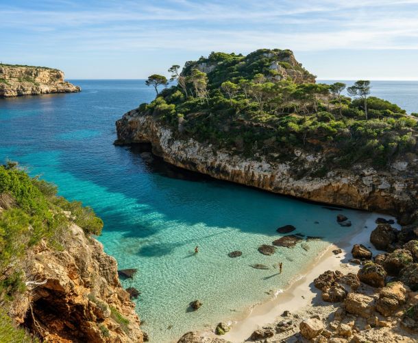 a beach with clear blue water next to cliff