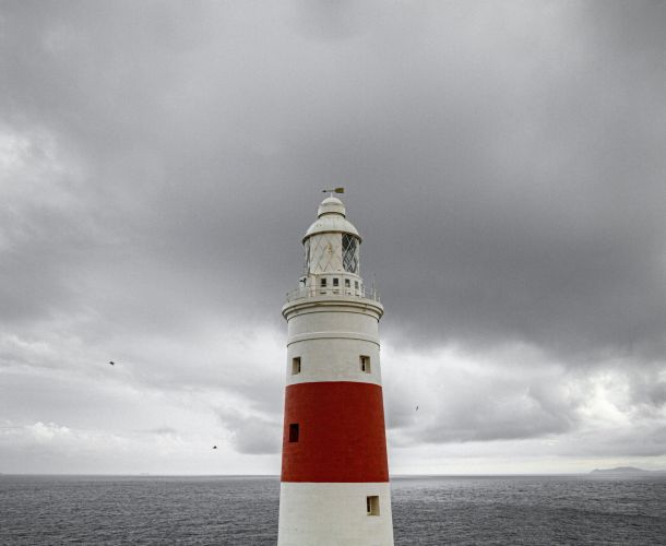 red and white lighthouse under a cloudy sky