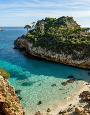 a beach with clear blue water next to cliff