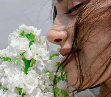 A woman is smelling a bunch of flowers.