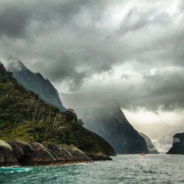 peak of mountain covered with clouds near body of water