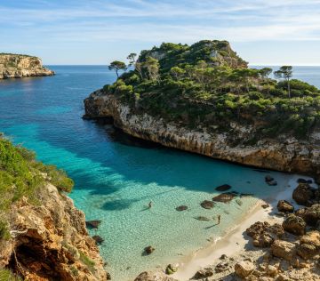 a beach with clear blue water next to cliff